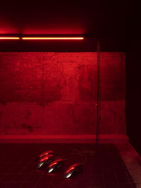 Hannah Perry, FENDER, 2026, Motorbike fenders, chainsm padlocks, red striplight, 222 x 115 x 90 cm